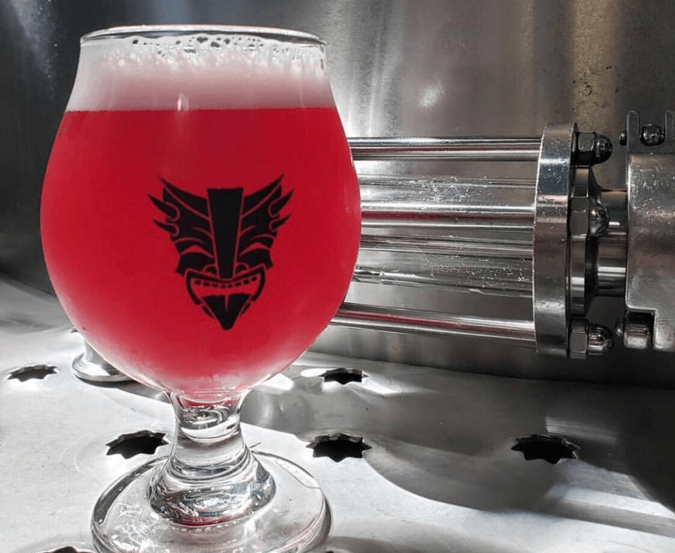 A glass of a berry ale sitting on a still