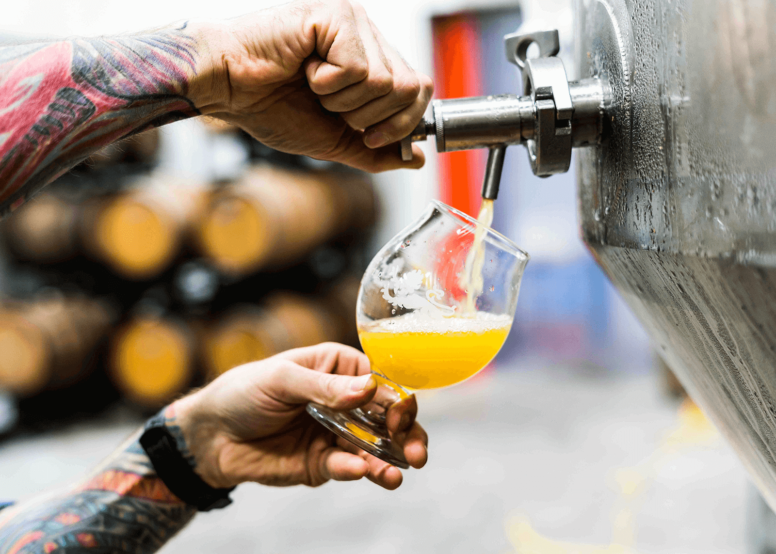 A person pouring a glass of beer from a still